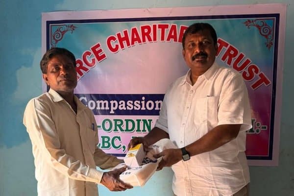 MCT leader distributing aid in front of the MERCE Charitable Trust banner