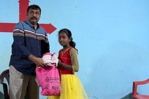 A girl receiving a gift package from an MCT leader inside a village church