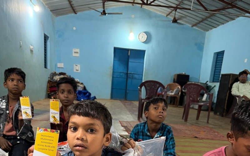 A boy holding a nutrition syrup package received at a MERCE health outreach camp