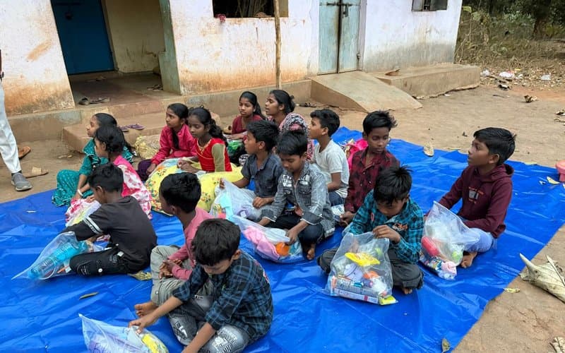 Children seated together receiving care packages at a MERCE Charitable Trust outreach event